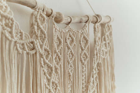 Beautiful boho macrame on wall panel. tapestry in the style of Boho made of cotton threads in natural color using the macrame technique for home decor and wedding decoration. light pastel colorsの写真素材