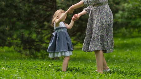 Little cute girl with her mother on the walk. Mother with child girl playing in garden. Woman with daughter huging and having fun outdoors.の写真素材