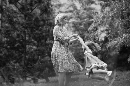 Little cute girl with her mother on the walk. Mother with child girl playing in garden. Woman with daughter huging and having fun outdoors.の写真素材