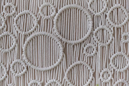Beautiful boho macrame on wall panel. tapestry in the style of Boho made of cotton threads in natural color using the macrame technique for home decor and wedding decoration. light pastel colorsの写真素材