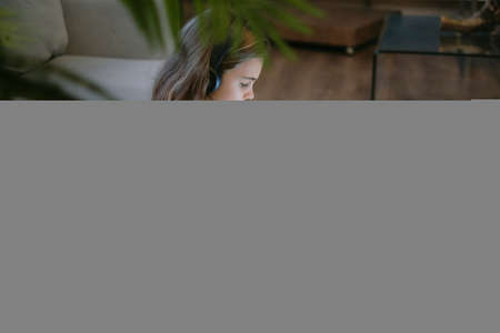 blurred photo. Teenage girl doing homework at a desk in her bedroom. teen girl school student write notes watch video online webinar learn on laptop.の写真素材