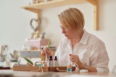 Close-up of a pipette with oil and a glass bottle. woman pouring perfume in bottle. Perfume creating workshopの写真素材