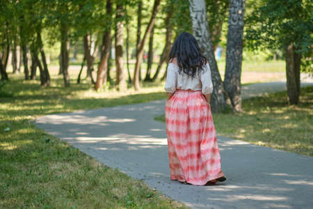 Middle-aged attractive woman with dark hair, enjoying nature in the forest. Walking among the trees in the sunlight. self-sufficient confident womanの写真素材