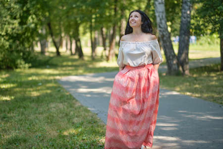 Middle-aged attractive woman with dark hair, enjoying nature in the forest. Walking among the trees in the sunlight. self-sufficient confident womanの写真素材