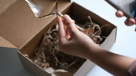 woman opening parcel indoors. woman opening and unpacking cardboard box parcel in living room at home. good delivery service.の写真素材