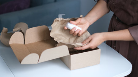 woman opening parcel indoors. woman opening and unpacking cardboard box parcel in living room at home. good delivery service.の写真素材