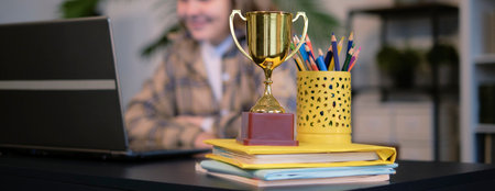 pretty teen girl with laptop and trophy on the table. little girl with a cup. Girl winner. little girl won the competition.の写真素材