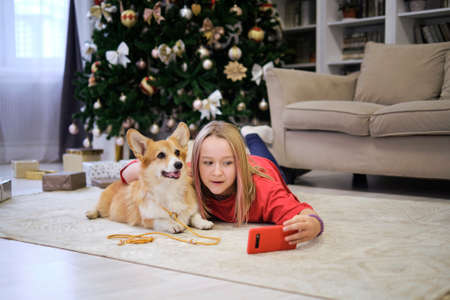 Friendship Concept. Teenage girl taking selfie with her dog at home. Dog lover with domestic animalの写真素材