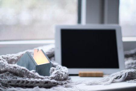 tablet with black screen, candle holders with lit candle at home. Selective focus. Hygge at home.の写真素材