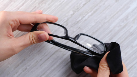 Cleaning a pair of dirty eye glasses with a microfiber.の写真素材