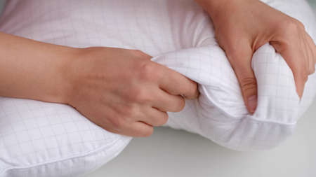 Young woman touching soft white pillow, closeup. how to choose a pillow, artificial fillingの写真素材