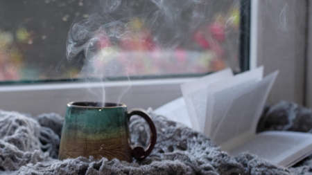 Steaming coffee cup on a rainy day window background. cozy atmosphere, in cold weather. Rainy Day Mood. warming home atmosphereの写真素材