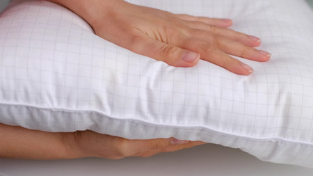 Young woman touching soft white pillow, closeup. how to choose a pillow, artificial fillingの写真素材