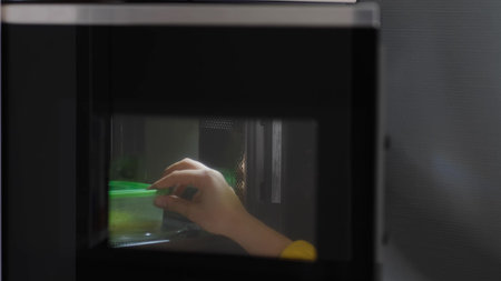 woman hands warming up a container of food in the modern microwave oven for snack lunch at home