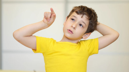 boy in a yellow T -shirt pulls up and looks upstairs. Contemplative Child Face, Close Up.