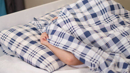 child covered himself with a blanket with his head, only his hands are visible. child insurance...