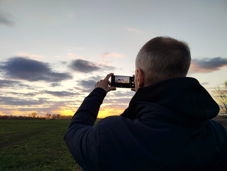 elderly male tourist taking a photo of the sunset