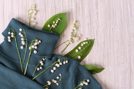 knitted sweater and a bouquet of fresh lilies of the valley. concept for dry cleaning and washing...