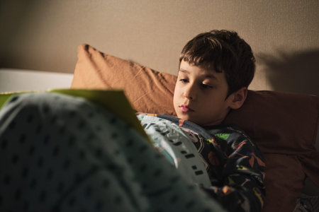 elementary school student reads a book in the evening before going to bed
