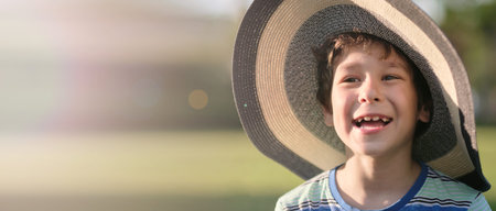 Portrait of a happy little boy in the sun smiles at the camera. Close-up portrait of a boy. banner