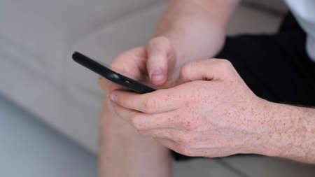 hands of a young man chatting on smartphone. Extreme close-up hands of unrecognizable man typing online message using mobile phone. Close-up.の写真素材