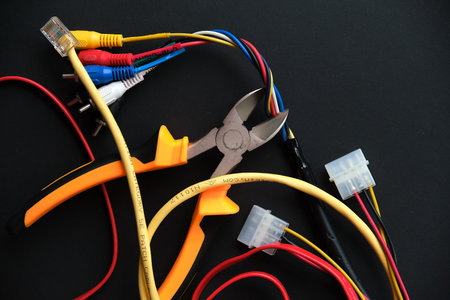 Pliers tool cutting red electric wire closeup on black background, service and repairing concept....