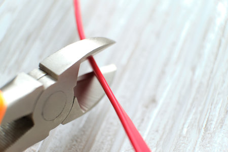 Electrician cuts electrical wires with pliers. Cutting pliers and cable. A cutter is cuting electrical wire or cable. Cutting wires with clippers. Metal nippers.の写真素材