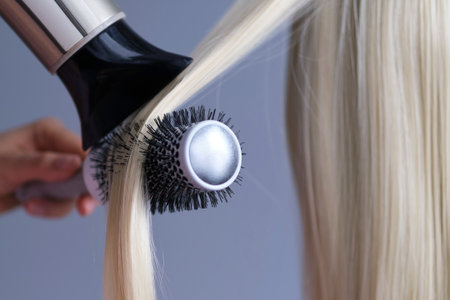 spa hair care concept. Drying blond hair with hair dryer and round brush.の写真素材