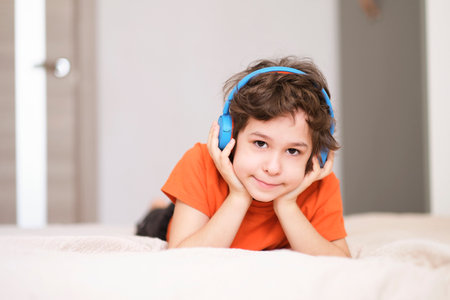 face of a smiling boy listening to music in blue headphones. High quality photo. Photo of little concentrated boy child with eyes closed listening fairy tale with headphones.の写真素材