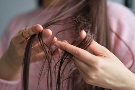 closeup female holding messy unbrushed dry hair in Hands. Hair damage concept.の写真素材