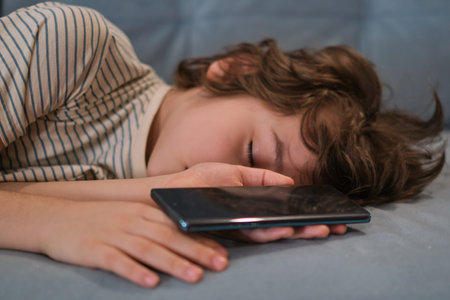 child fell asleep while playing on the phone. a quiet moment of a child at rest, highlighting the importance of family time and the need for children to unwind and relax after a busy day.の写真素材
