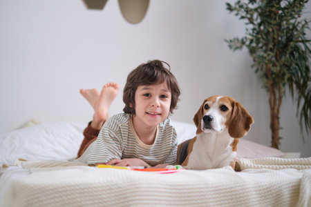 Happy boy embracing rescued beagle on bed, both smiling. adopt a loving pet and create lifelong memories together.の写真素材