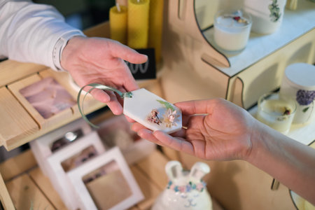 Handmade Aromatic Sachet Sale: A woman at a market hands over artisanal sachet to a customer, showcasing craftsmanship and natural scents.の写真素材