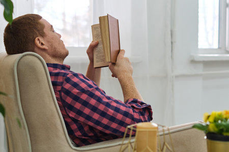 Man relishing a page-turner from the comfort of his home, enclosed by a leafy. The Benefits of Reading: How Diving into a Good Book Can Improve Your Mental Healthの写真素材