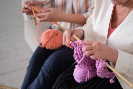 two senior women use their knitting skills to create warm, pink scarves and hats for breast cancer patients, symbolizing hope, love, and support for those battling the disease.の写真素材