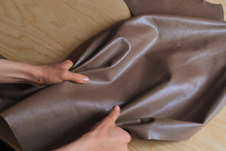 talented woman leather artisan holding a roll of exquisite leather in her workshop, emphasizing her...