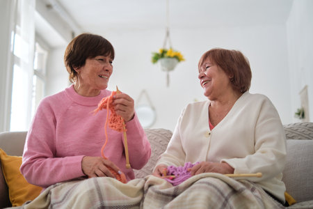 two senior women knitting and reminiscing together. maintaining strong family bonds and social interaction to combat loneliness and isolation in older adults.の写真素材