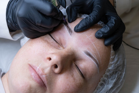 close-up reveals the precision of the microblading needle, delicately crafting each hair stroke. Witness the transformation of sparse brows into fuller. microblading or eyebrow tattooingの写真素材