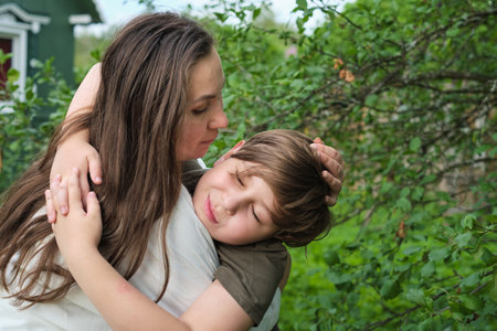 A mother and son share a joyous moment in a lush park, embodying the essence of authentic family bondsの写真素材