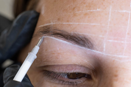 Close-up of a woman undergoing precise eyebrow mapping prior to permanent makeup application.の写真素材