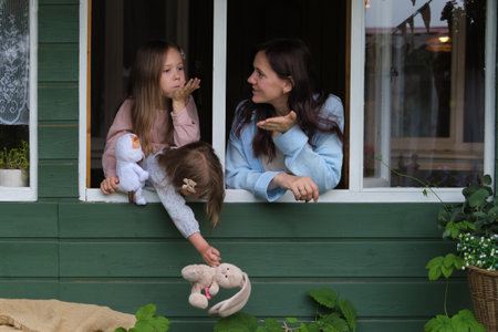 mother and her children find brightness, sharing playful gestures and radiant smiles from their window perch. Mindfulness and presence: living in the moment with our loved ones.の写真素材