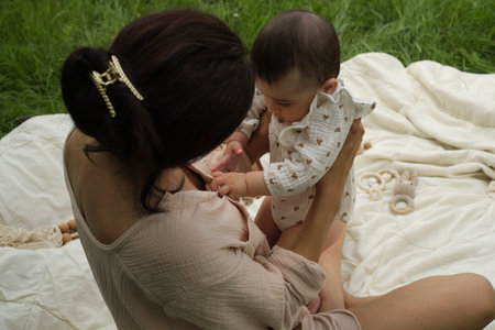 happy mother holds her baby close, their laughter mixing with the sounds of nature, epitomizing the...
