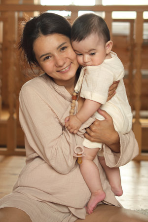Maternal Bliss: An elated mother cherishes quality time with her baby, enveloped in the dappled daylight of their rustic sanctuaryの写真素材