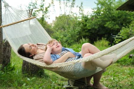 private oasis forms as a mother and her son find their comfort zone in a hammock, away from the hustle and bustleの写真素材