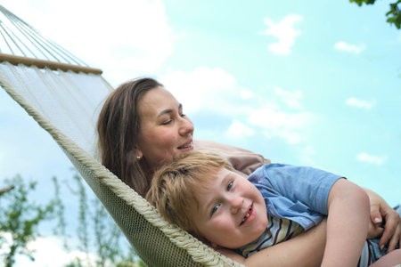Embracing the Present: A mindful pause between a mother and her child creates an intimate space within the comfort of a hammock.の写真素材