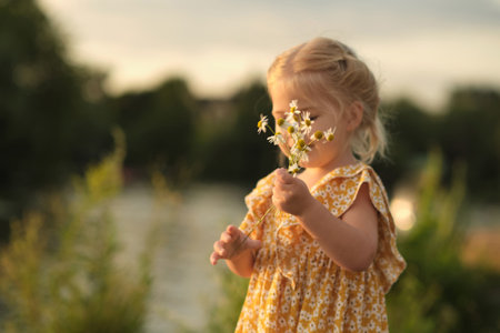 little girl, the epitome of youthful happiness and innocence, smiles while holding a bouquet of daisies. Her joy underscores the importance of quality family time and instilling positive valuesの写真素材