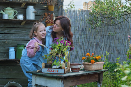 Motherly Love: In the garden, mom and daughter nurture seedlings together, sharing knowledge and bonding.の写真素材