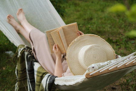 Submerged in tranquility, a woman reads in a hammock, embracing harmony and the slow life, providing a peaceful break from city clamorの写真素材