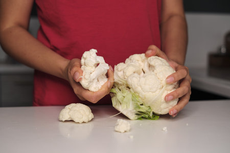Elegant hands dissect a cauliflowers rainbow, painting the kitchen with nature. Venture into a world where wellness meets everyday culinary art.の写真素材