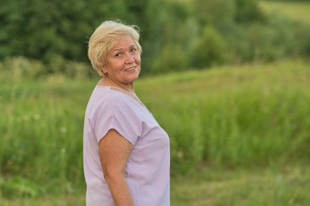 The gentle smile of a mature woman outdoors at sunset. Highlights the growing focus on natures role in enhancing quality of life for the aged.の写真素材